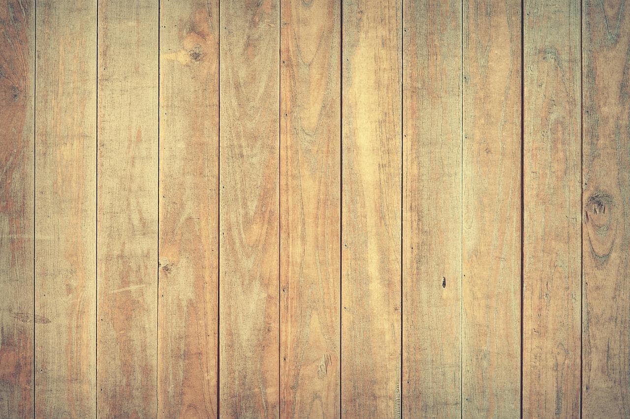 Multiple vertical laminate flooring planks in warm honey-gold wood tones with natural grain patterns.