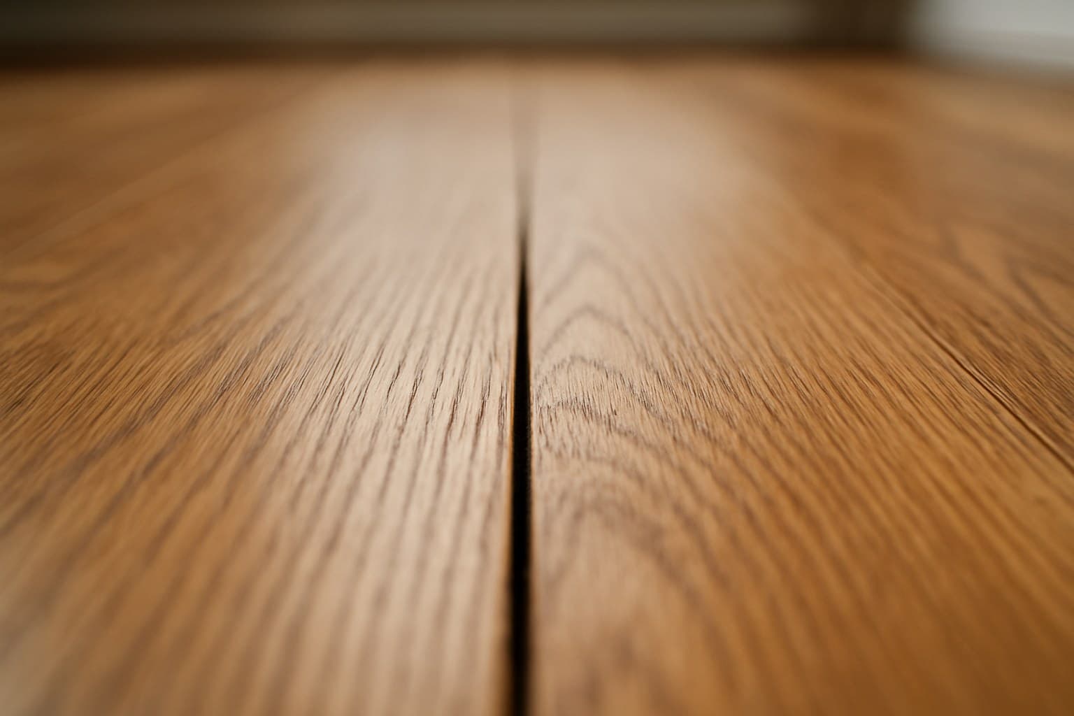 Narrow gap between hardwood floorboards showing a common post-install squeak issue
