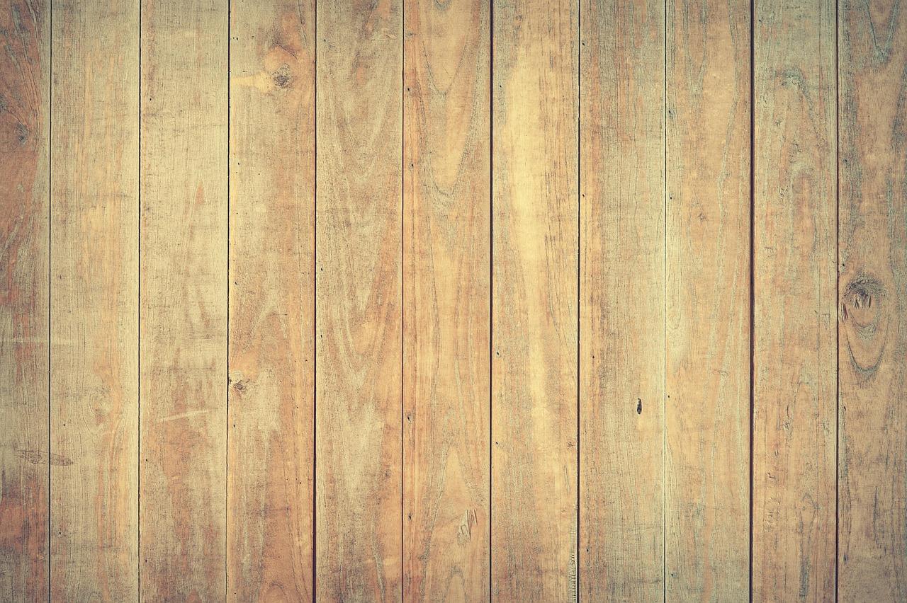 Multiple vertical laminate flooring planks in warm honey-gold wood tones with natural grain patterns.